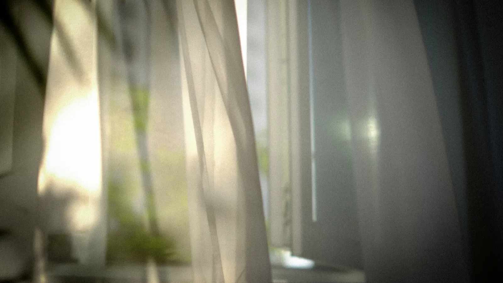 “Luz contenida entrando por una cortina; quietud que sugiere presencia y ausencia.”